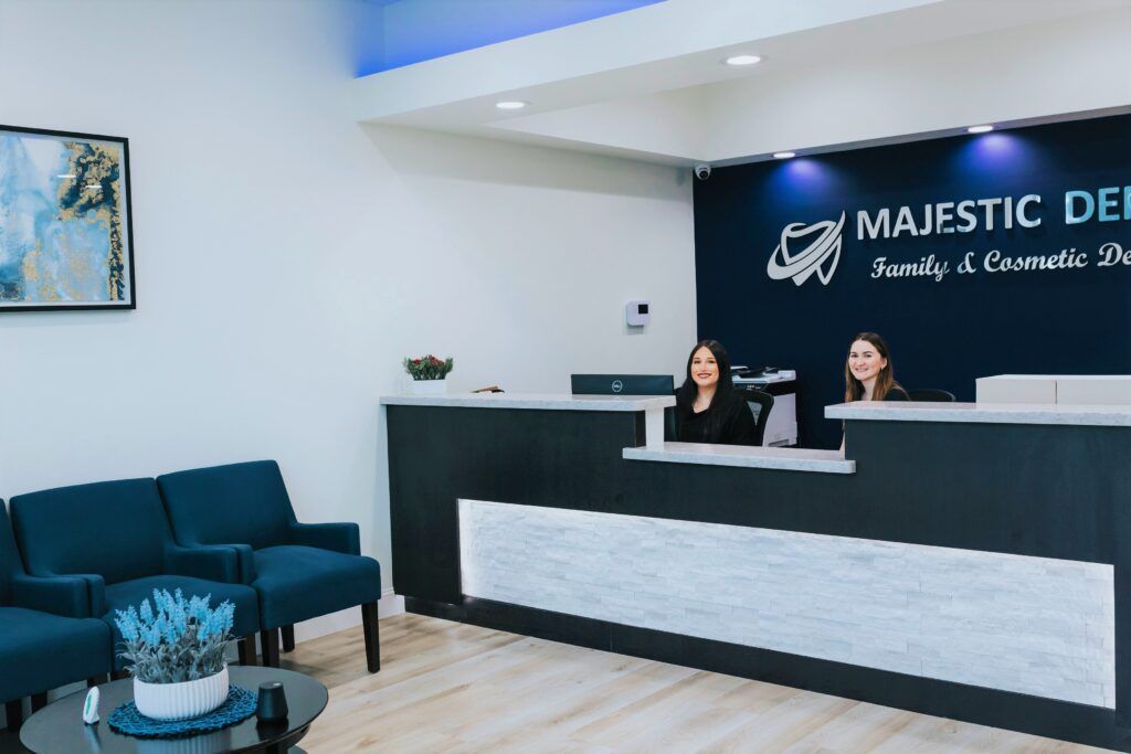 Two smiling dental team members sitting at front desk of Majestic Dental in The Woodlands