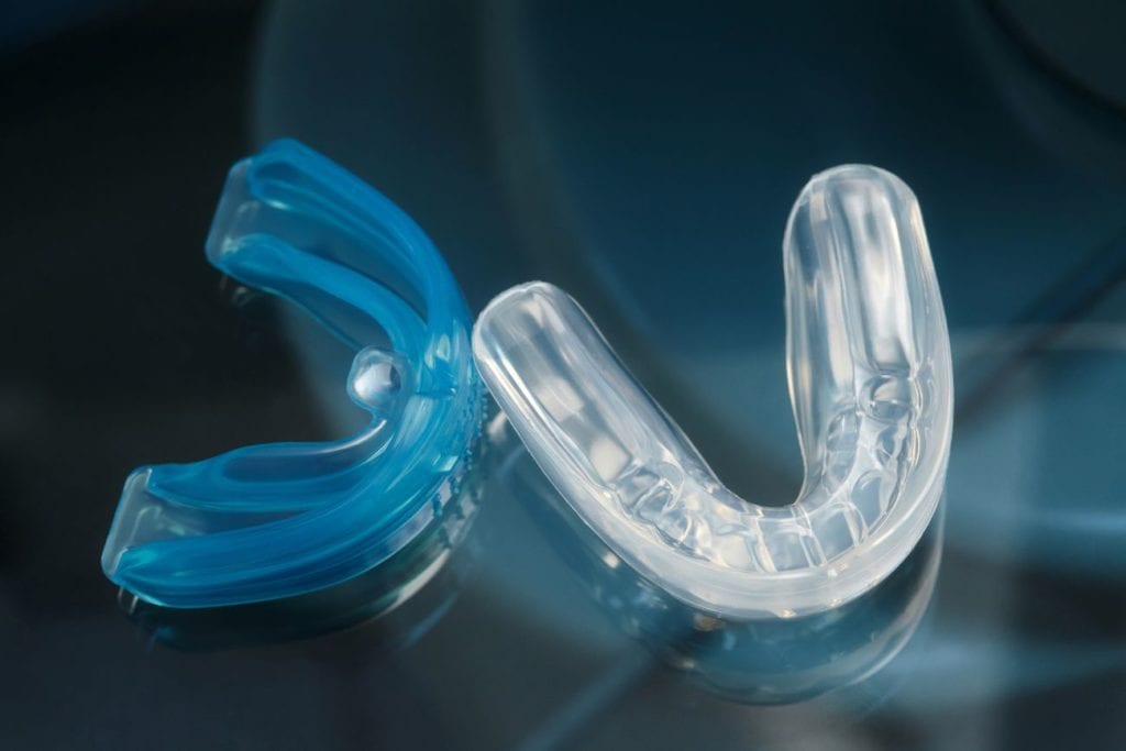 Two clear custom mouthguards in The Woodlands against a dark blue background