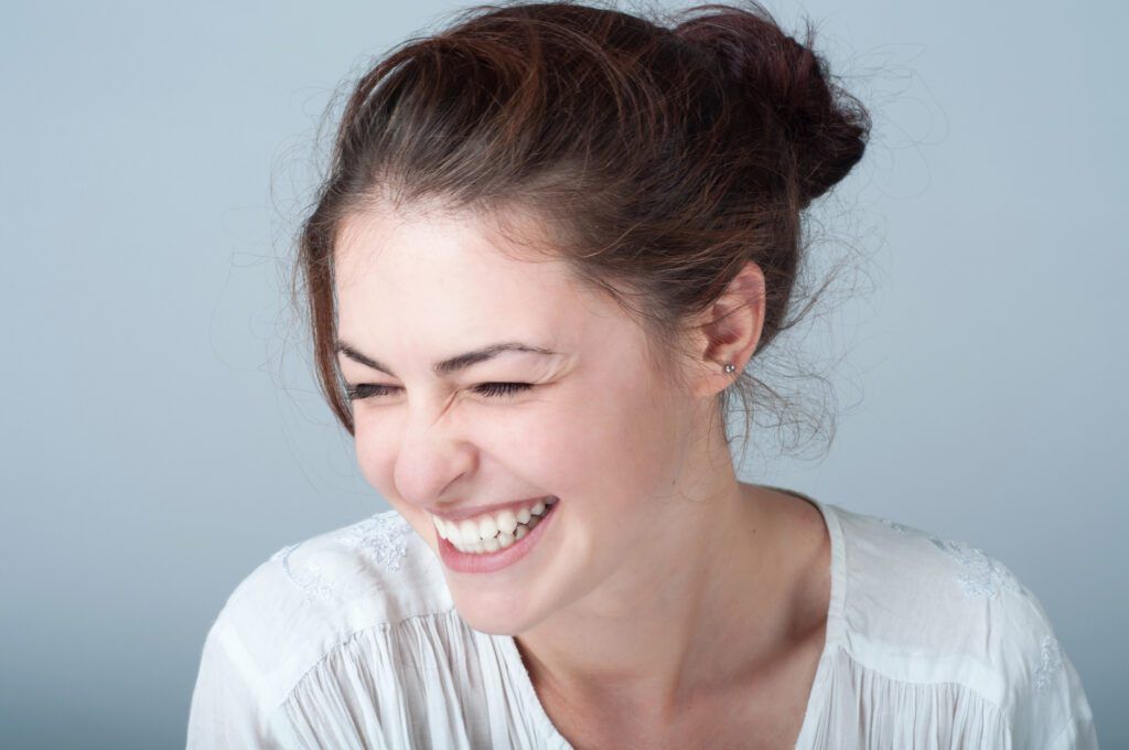 Brunette woman grinning after cosmetic dentistry in The Woodlands