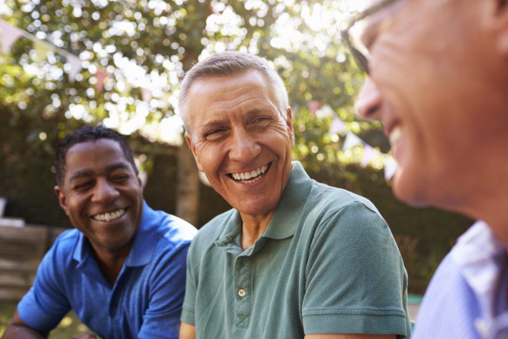 Three men laughing together outdoors after restorative dentistry in The Woodlands
