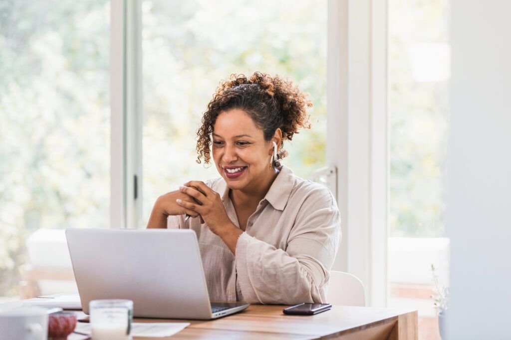 Woman looking at her laptop and smiling after dental bonding in The Woodlands