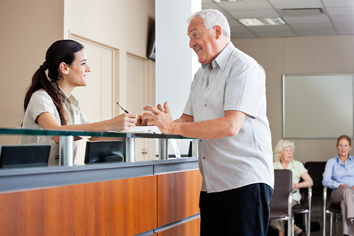 A man speaking with the front desk staff at a dental office