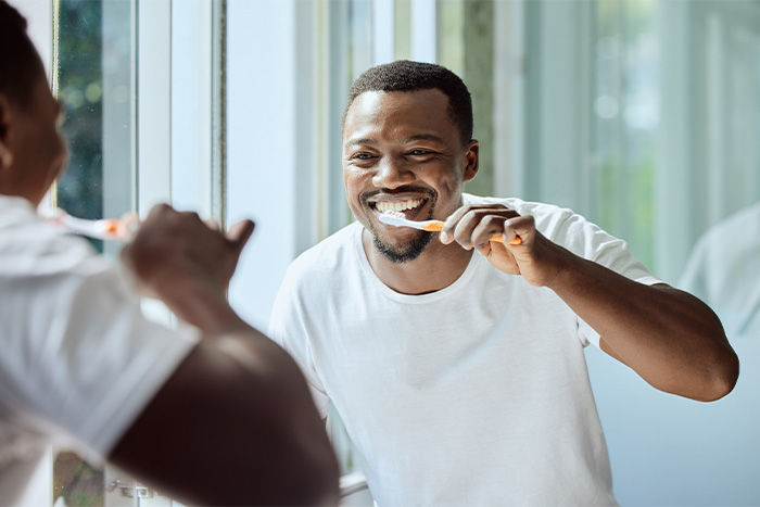Man brushing his teeth in the bathroom mirror