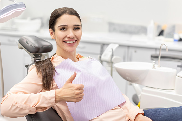 Woman in dental chair giving a thumbs up while visiting emergency dentist in The Woodlands