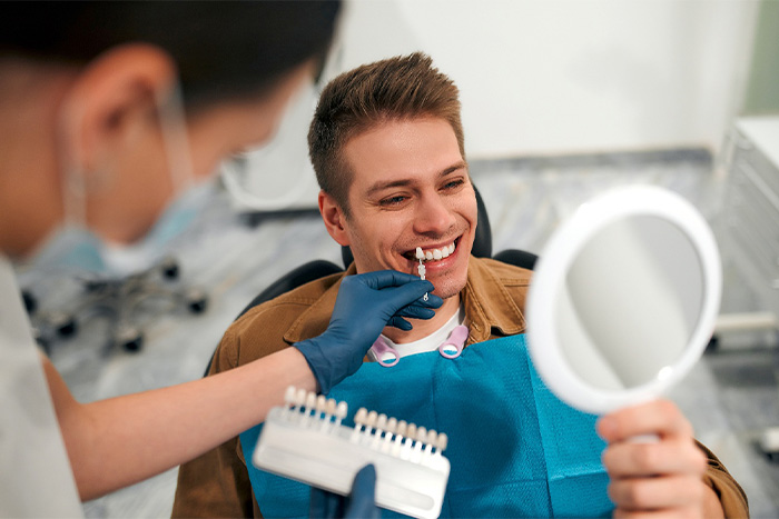 Dentist helping smiling patient select shade of veneers.