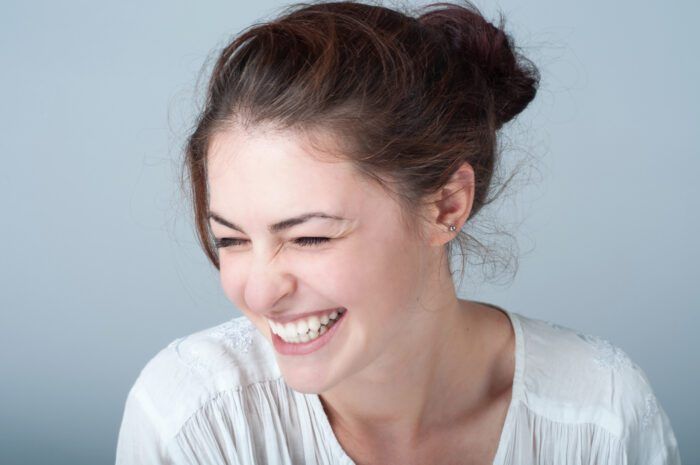 A woman with a bright smile and laughter, showcasing her healthy teeth in a dental setting.
