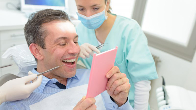 Man smiling into mirror and looking at his tooth-colored filling.