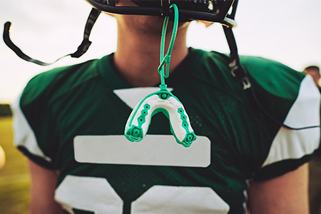 An athletic mouthguard hanging from a football player's helmet.