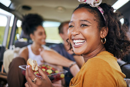 Patient smiling while eating with friends in car.