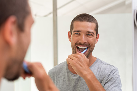 Person brushing teeth at home with fluoride toothpaste.